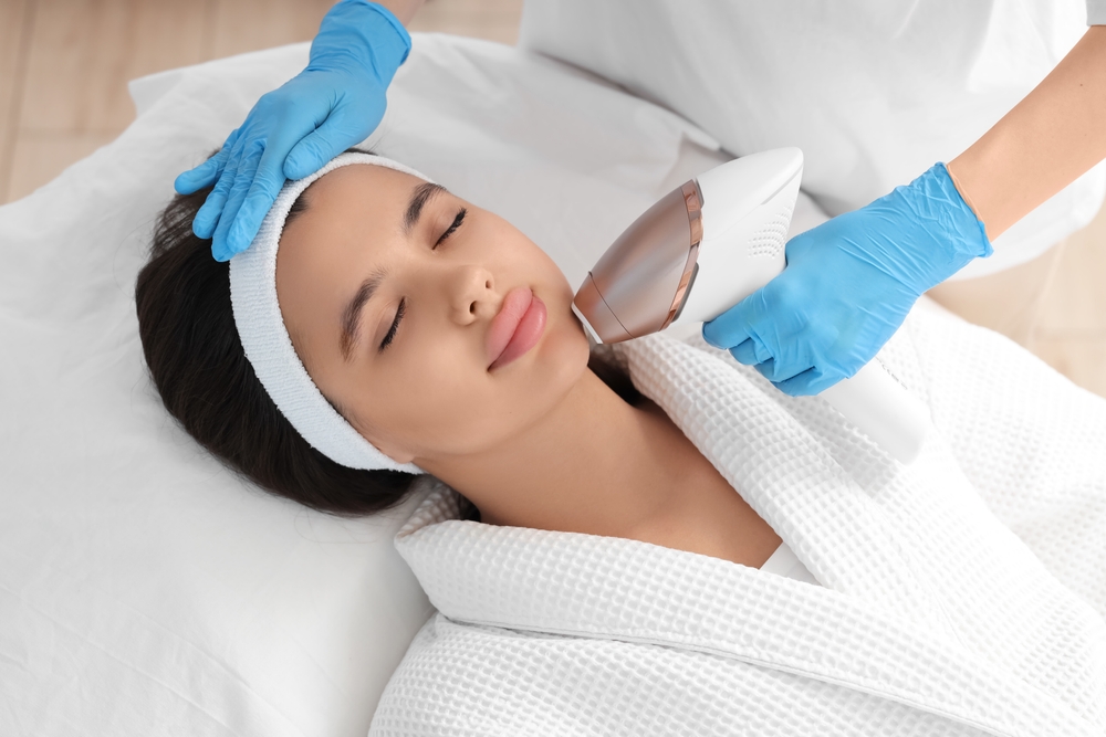 Beautician epilating woman's face in salon